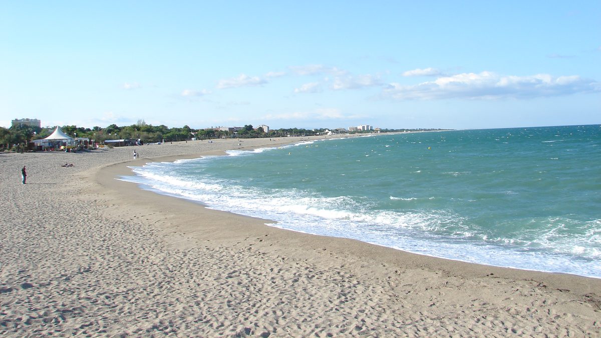 The long, fine sandy beach of Argelès-Plage, the waves and the coastline stretching north under a blue sky