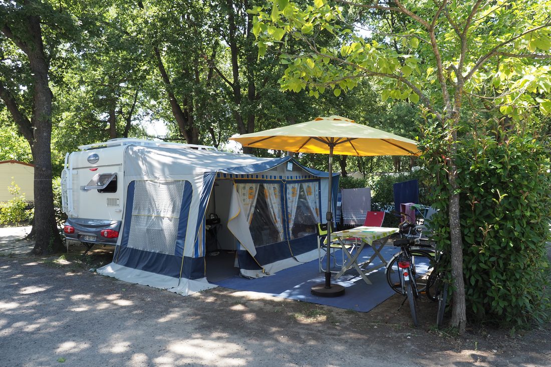 Kampeersfeer: caravan onder de bomen met fietsen en parasol, l'Étoile d'Or