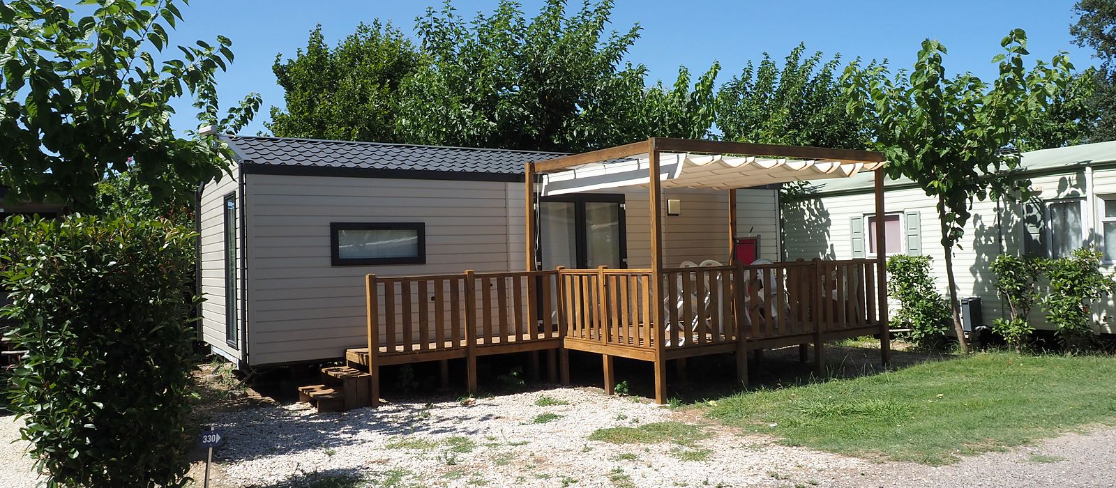 Mobil-home avec terrasse couverte en bois, entouré de verdure, au camping l'Étoile d'Or à Argelès-sur-Mer