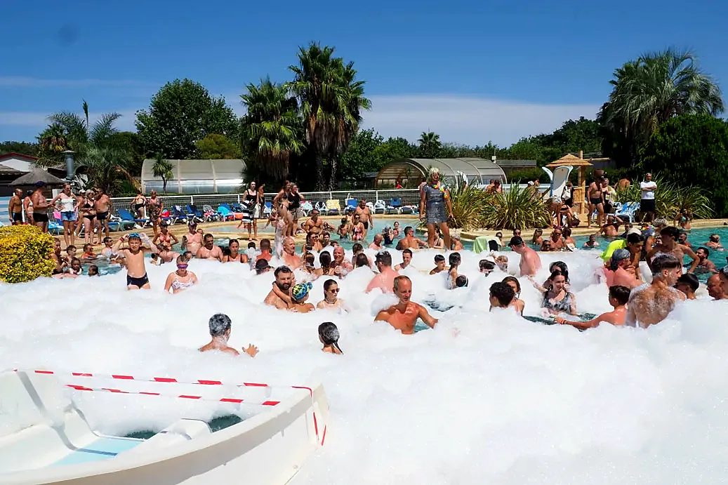 Schuimfeest in het zwembad van camping l'Étoile d'Or: gasten in het schuim dat over het bad wordt gespoten