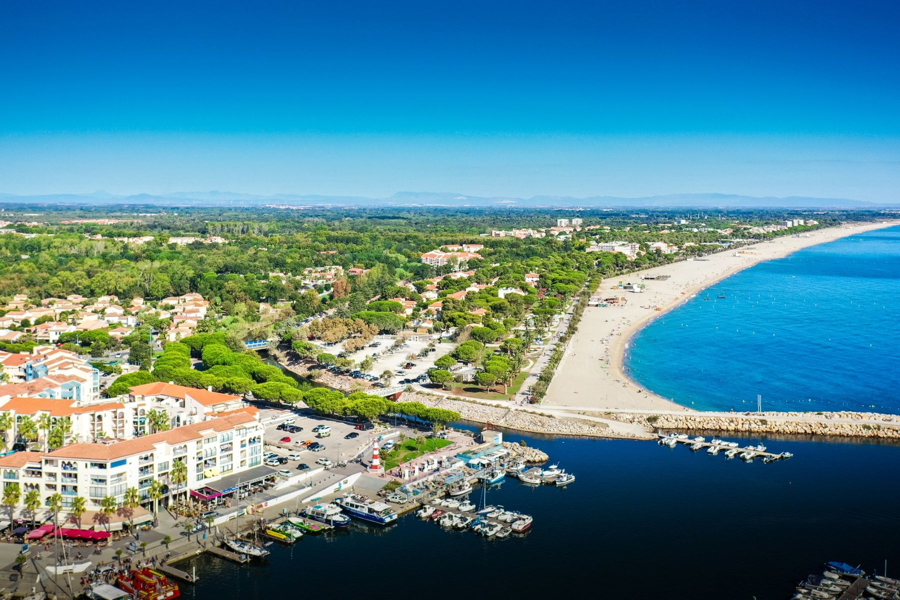 Aerial view of Argelès-sur-Mer: the long beach, the marina and the town, with the mountains on the horizon